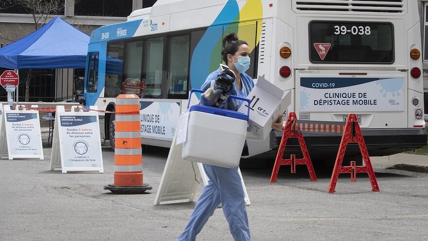 Une professionnelle de la sant marche devant un autobus transform en clinique de dpistage