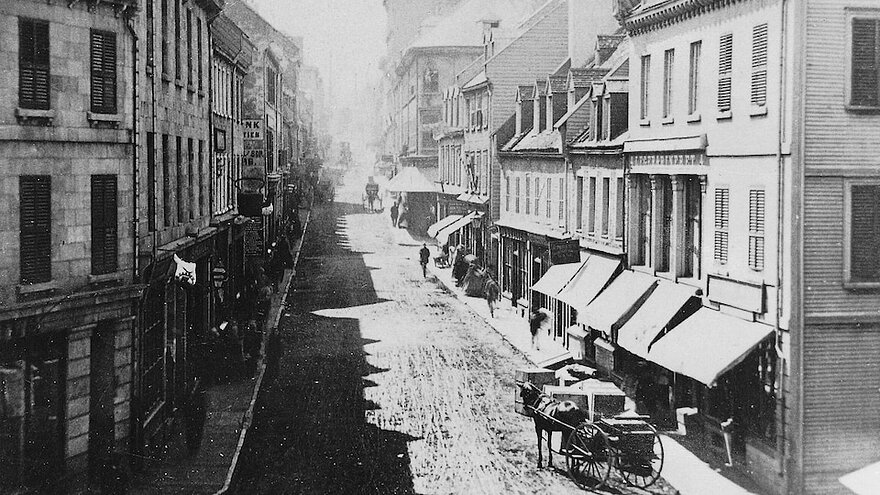 La rue Saint-Jean vers 1865. La bouilloire est déjà visible en façade de la quincaillerie.
