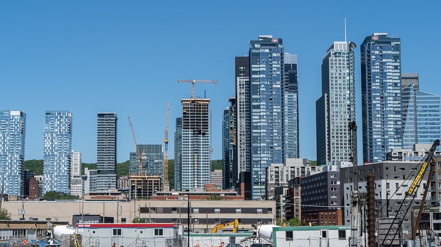 Près d'un chantier de Griffintown, des grues sont visibles autour des grattes-ciel du centre-ville de Montréal.