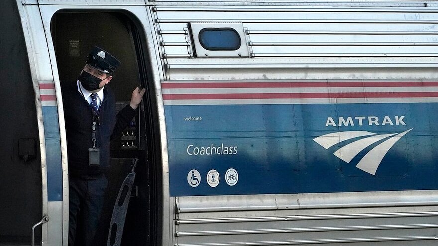 Un chef de train à la porte d'un train Amtrak à l'arrêt.