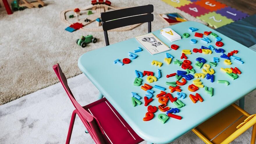 Une petite table pour enfants est recouverte d'un jeu avec des chiffres et des lettres dans une salle qui accueille des enfants.