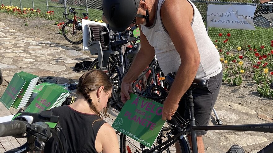 Une femme installe une affiche sur un vélo.