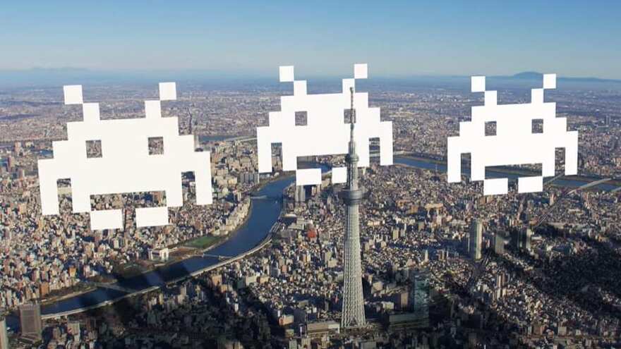 Trois extraterrestres pixelisés au-dessus d'une grande ville.