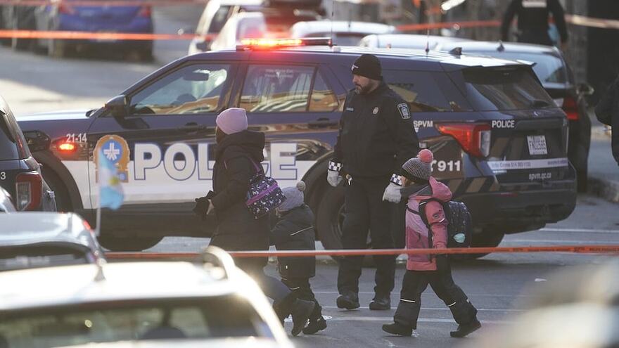 Un policier et des enfants au milieu de voitures de patrouille et de cordons de sécurité.