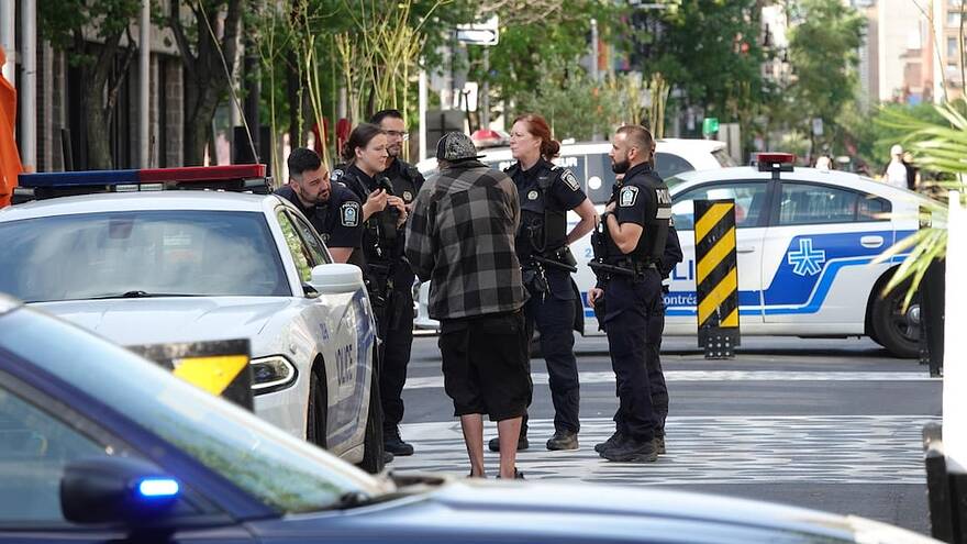 Des agents du Service de police de la Ville de Montréal lors d'une opération auprès d'une personne en situation d'itinérance sur la rue Sainte-Catherine, à Montréal.