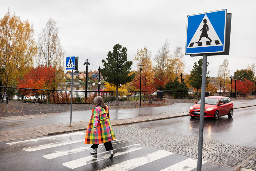 The writer traversing a road with a “woman crossing” sign. Photograph: Elin Berge