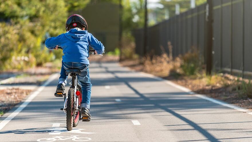 Un enfant fait du vélo sur une piste cyclable.