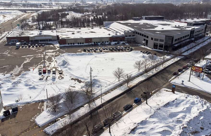 Le terrain vague est situé devant un espace commercial qui abrite notamment des bureaux de Service Canada.