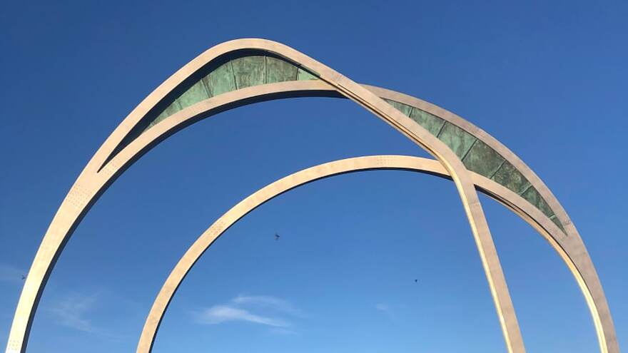 Des arches en métal sur fond de ciel bleu.