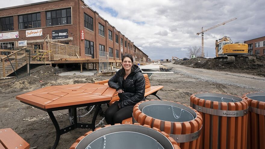 Véronique Houle est entourée de bacs et est assise à une table dans la ruelle en construction.