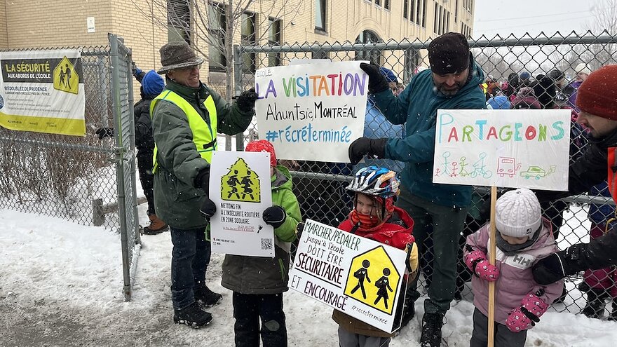 Manifestation d'hommes et des enfants tenant des pancartes sur la sécurité routière près des écoles.