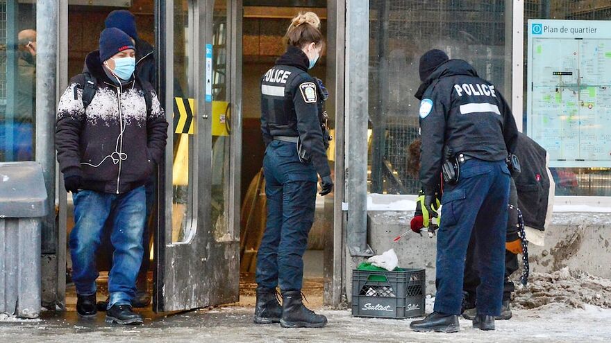 Des agents du Service de police de la Ville de Montréal interviennent auprès d'un itinérant au métro Berri-UQAM.