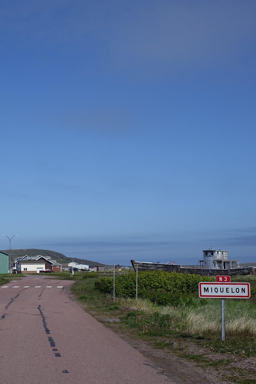 Une route menant à Miquelon avec des maisons au loin.