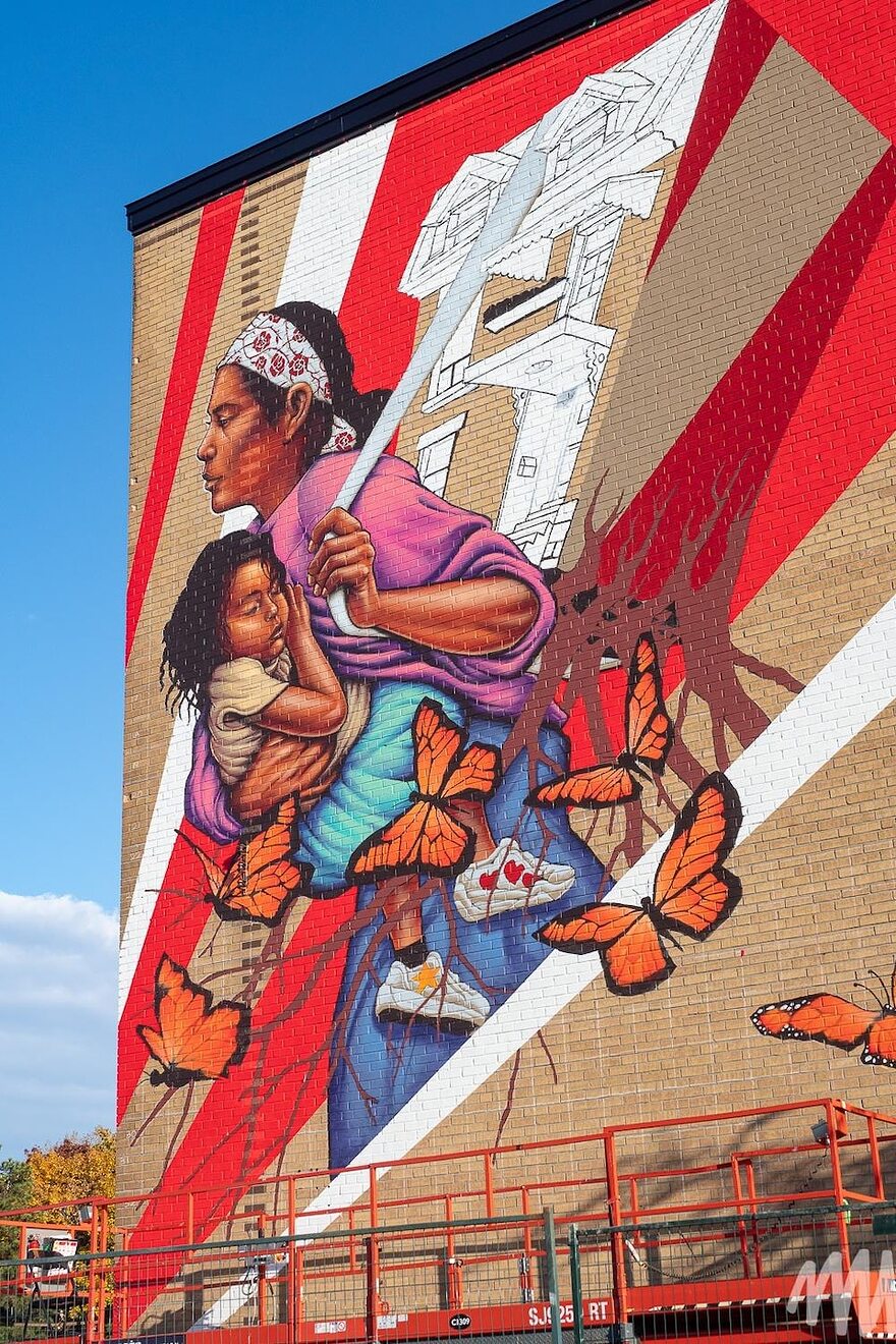 Photo d'une murale représentant une femme tenant un enfant dans les bras et une maison sur son dos.