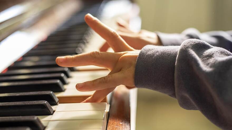 Des mains d'une jeune personne jouant du piano.