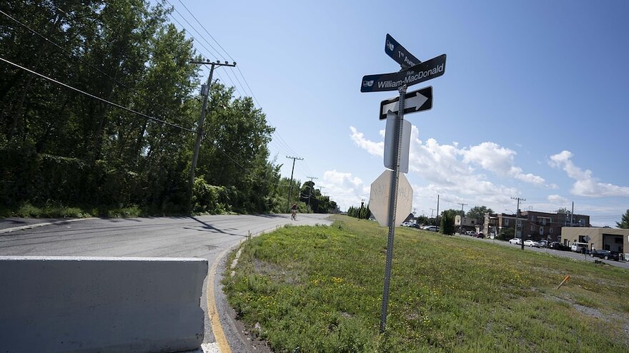 Le panneau indiquant le chemin William-Macdonald et la première Avenue sur le terrain gazonné bordant un chemin pavé.