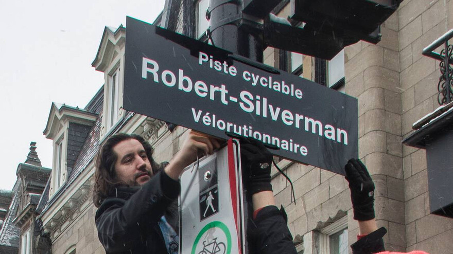 Karim Kammah attaches a sign at the corner of St-Denis and Roy St. in Montreal on March 12, 2022 in a ceremony to honour Robert (Bicycle Bob) Silverman, who died the previous month. The group will get its wish, as the bicycle path on St-Denis is named in Silverman’s honour. John Kenney Montreal Gazette files