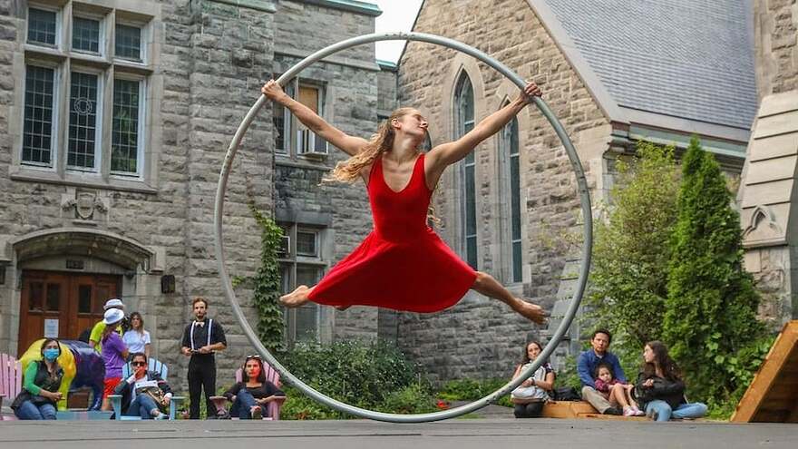 Une artiste de cirque en robe rouge se tient en équilibre dans un anneau géant.