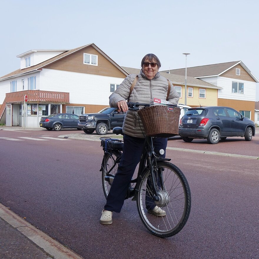 Une femme dans la soixantaine à vélo dans une rue du village de Miquelon.