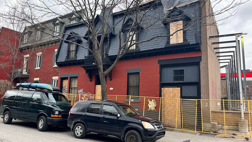 Une maison de chambres placardée en briques rouges avec un toit d'ardoise. © René Saint-Louis / Radio-Canada