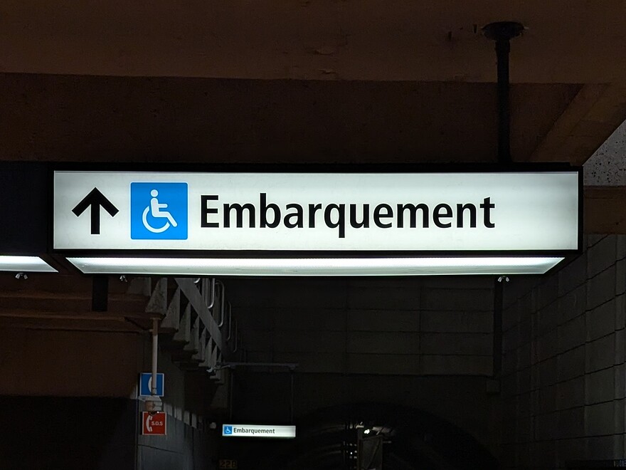 Backlit métro signage indicating where wheelchair users should board.