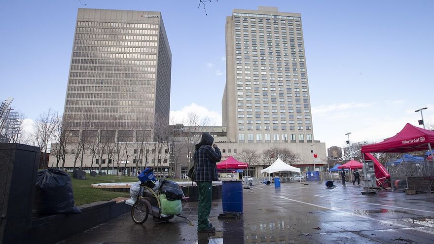 Une personne itinérante au cœur de la place Émilie-Gamelin face à l'hôtel de la Place Dupuis, au centre-ville de Montréal.