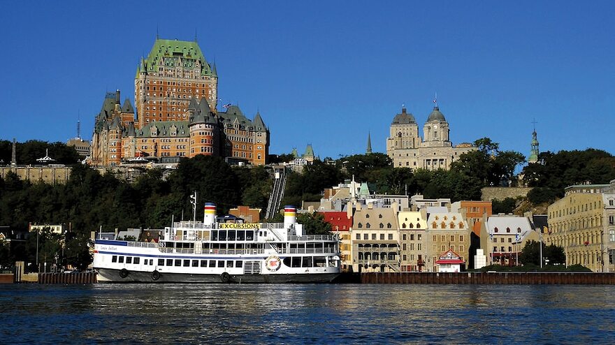 Boat passing in front of old buildings on the waterfront in Quebec City.