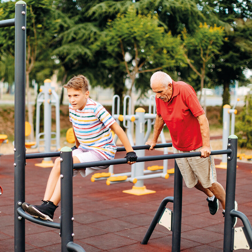 Un grand-père et son petit-fils en train d'utiliser des modules d'exercice extérieurs