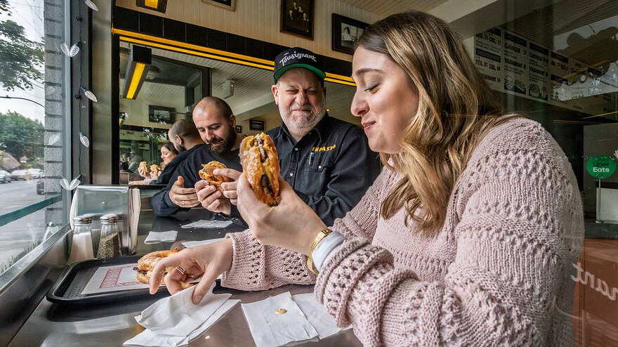 Alyssa Brandone, Michele Forgione and Dean Giannarakis, right to left, chow down on hamburgers between honey glazed doughnuts instead of traditional buns at Chez Tousignant on Thursday, May 29, 2025. Dave Sidaway Montreal Gazette