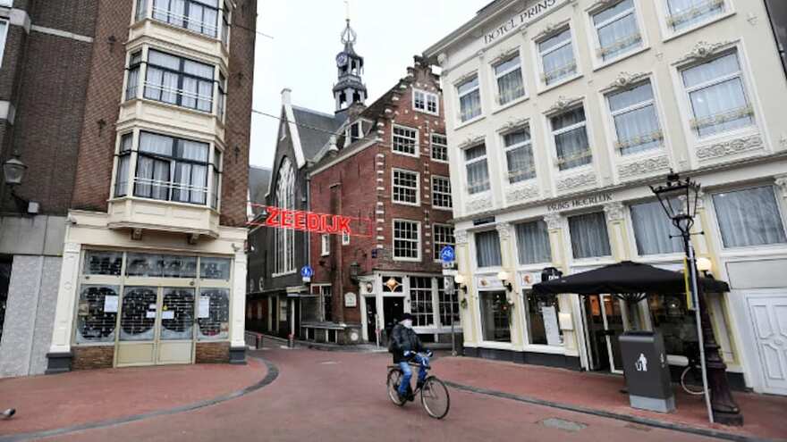 Une rue d'Amsterdam dans laquelle circule un cycliste.