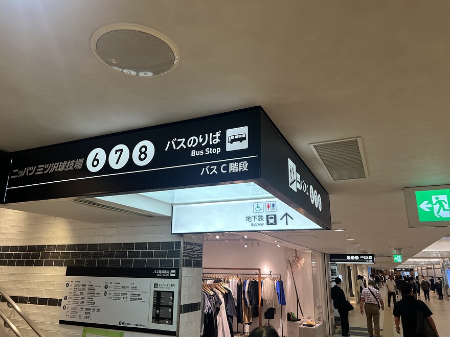 Overhead sign showing bus gates and arrow pointing to train, with wall showing bus routes and elevator access