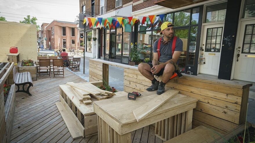 Un homme construisant une terrasse prend une pause, assis sur celle-ci.