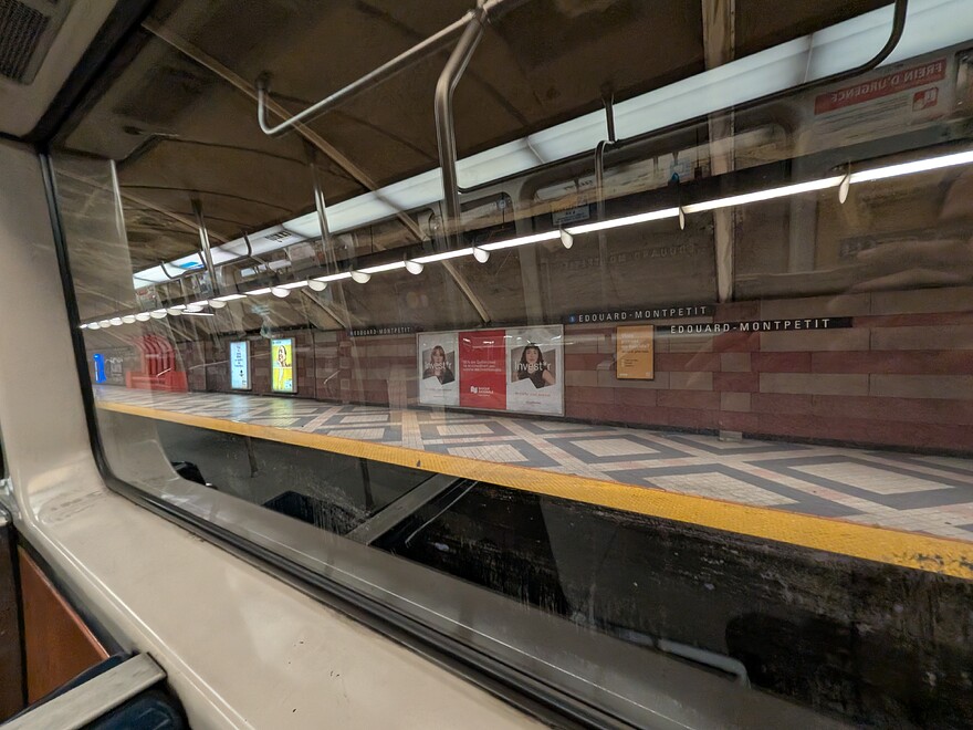 Installation en cours des bandeaux de quai à la station Édouard Montpetit. On peut voir que ceci est incomplet et qu'il y a encore des affiches temporaires affichant le nom de la station.