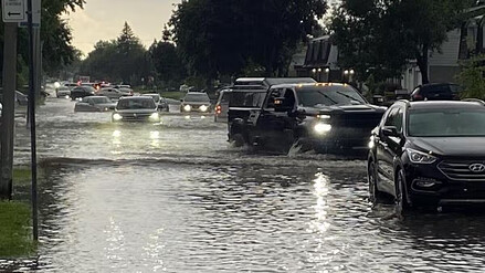 Des véhicules circulent dans une rue inondée de l'arrondissement de Pierrefonds-Roxboro, à Montréal. – Photo : Radio-Canada / Bruno Lavoie