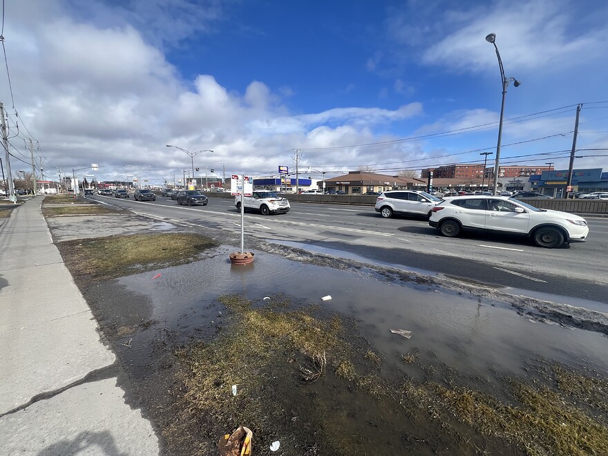 Bus stop in grass and large puddle of water