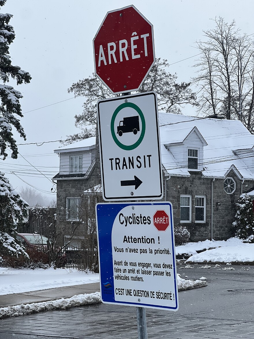 Sign with text: Attention ! Vous n'avez pas la priorité. Avant de vous engager, vous devez faire un arrêt et laisser passer les véhicules routiers. CEST UNE QUESTION DE SÉCURITÉ!