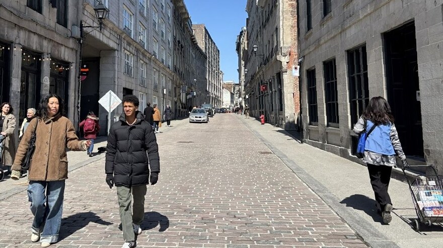Des personnes marchent dans la rue sur le pavé de la rue Saint-Paul, après les travaux de réaménagement qui en ont fait une rue partagée.