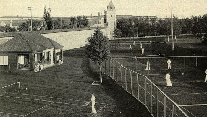 Des joueurs élégants sur les courts sur gazon longeant les fortifications au début du 20e siècle.