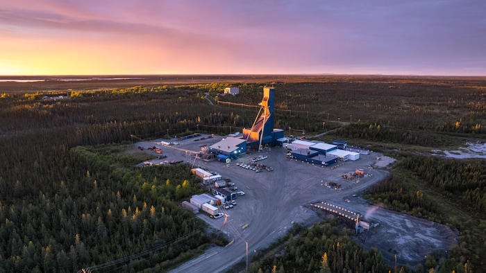 Photo aérienne d'un chevalet de mine et des bâtiments autour au milieu d'une vaste forêt.