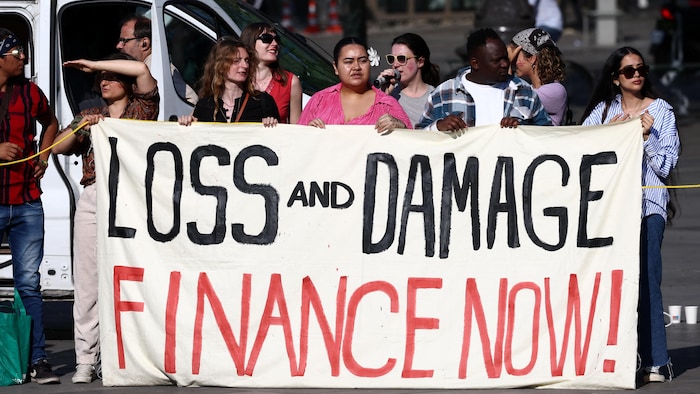 Des militants écologistes tiennent une banderole avec le slogan Pertes et dommages, financez maintenant, lors d'une action de grève pour le climat à Paris, en France, le 23 juin 2023.