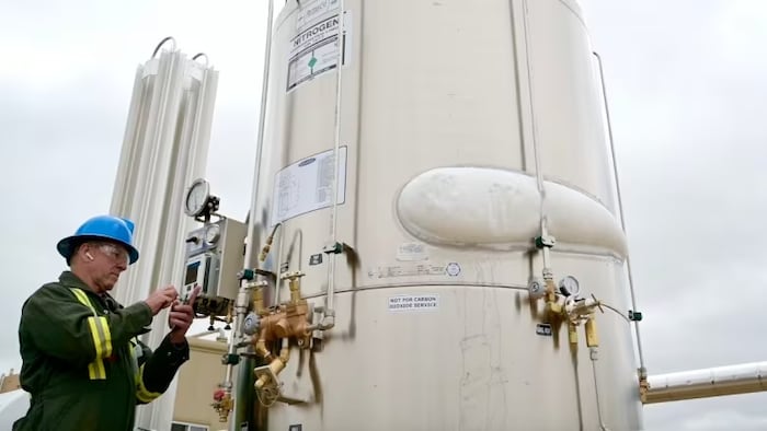 Un technicien travaillant sur un réservoir d'azote liquide destiné à remplacer le méthane sur les sites de forage.