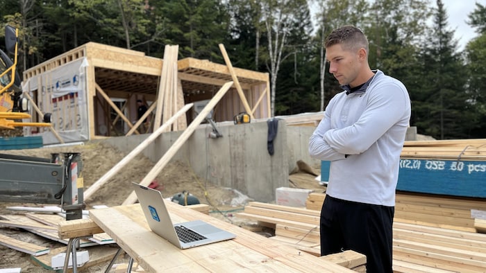 Ghyslain Octeau-Piché écoute la vidéo d'Hydro-Québec sur le chantier d'une maison qui attend un branchement.