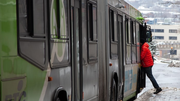 Un usager du Réseau de transport de la Capitale embarque dans un métrobus.