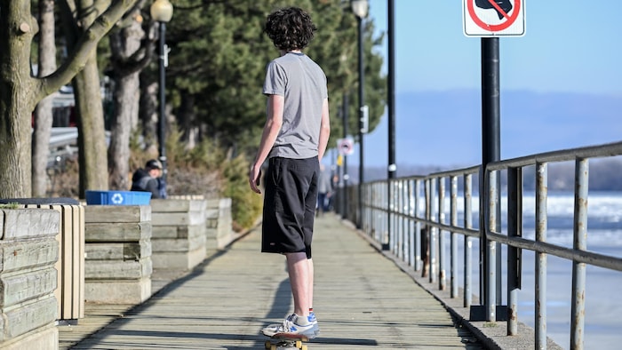 Un garçon fait de la planche à roulettes le long d'un cours d'eau.