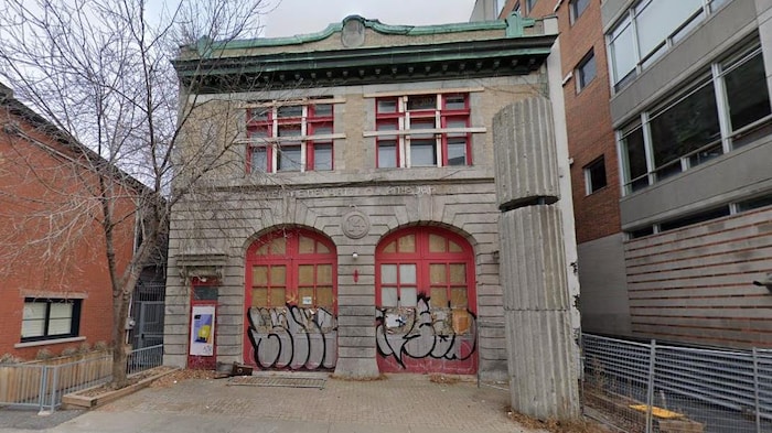 La caserne numéro 14 avec ses deux grandes portes pour laisser sortir les camions de pompiers. Les portes sont couvertes de graffitis et les fenêtres du deuxième étage sont barricadées.