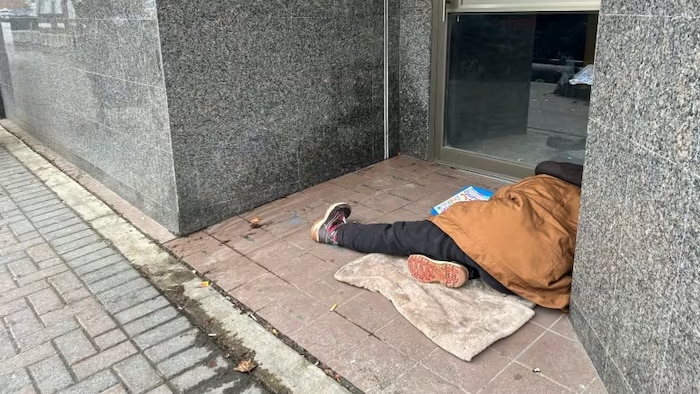 Une personne couchée sur le sol devant une porte d'entrée.