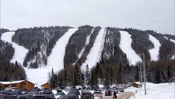 Une montagne avec des pistes de ski en hiver avec des skieurs et une remontée mécanique