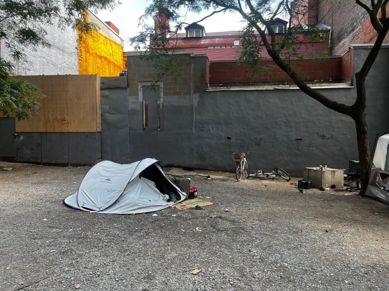 A tent belonging to a person experiencing homelessness is seen in an alley in Chinatown. Two bikes lie on the ground beside it.