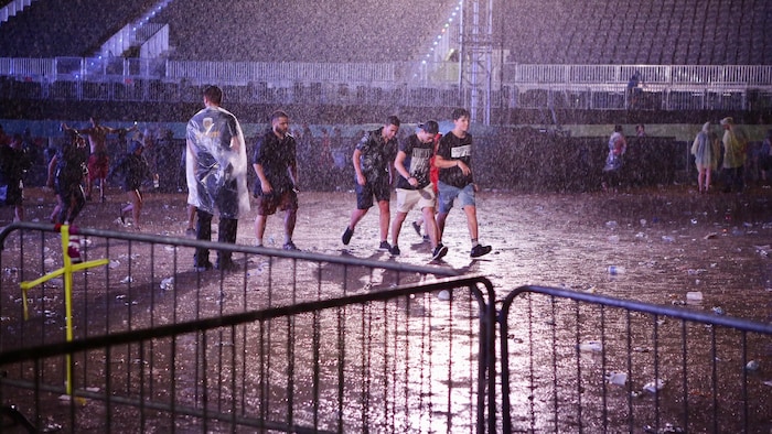 Des festivaliers sous la pluie à un spectacle de musique.