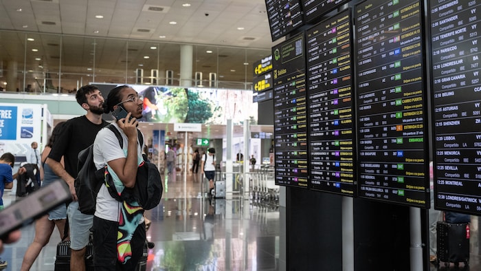 Des passagers regardent un écran affichant les vols retardés à l'aéroport de Barcelone le 19 juillet 2024 à Barcelone, en Espagne. Les entreprises, les agences de voyages et les utilisateurs de Microsoft du monde entier font aujourd’hui partie des personnes touchées par une panne technologique.